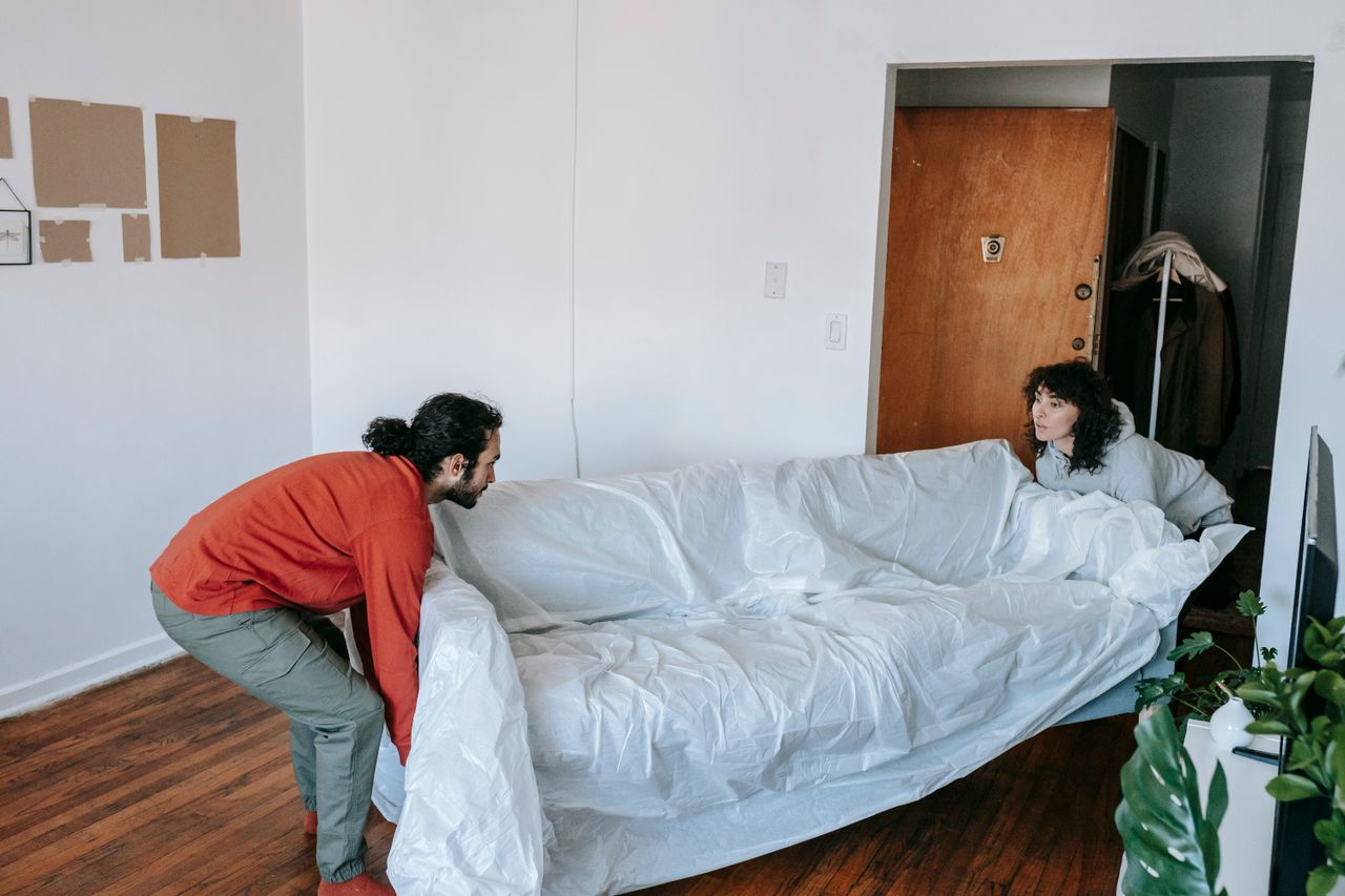 Un couple soulève ensemble un canapé en emménageant dans un nouvel appartement.